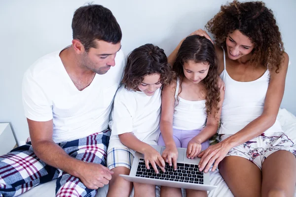 Familie met behulp van laptop samen op bed — Stockfoto