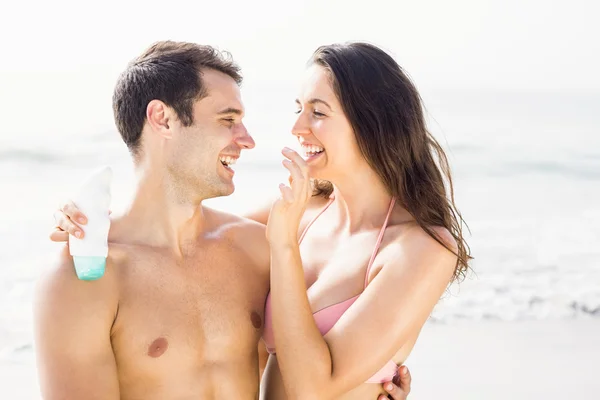 Mulher feliz aplicando hidratante no nariz do homem — Fotografia de Stock