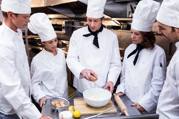 Chef cuisinier enseignant à son équipe à préparer une pâte — Photo