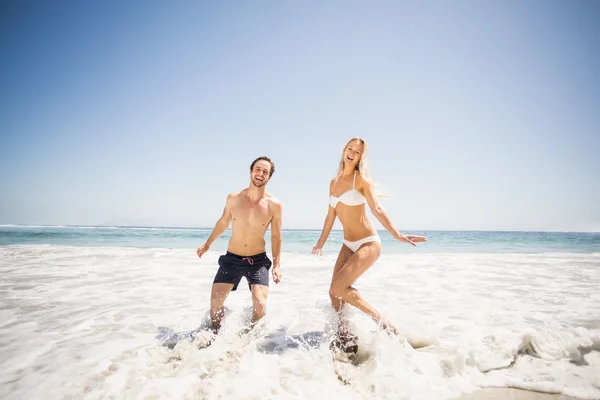 Casal feliz se divertindo na água na costa — Fotografia de Stock