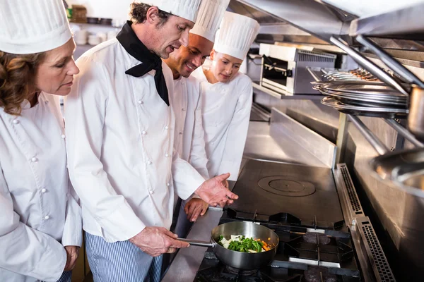 Erfahrener Küchenchef erklärt seinen Kollegen in der Küche — Stockfoto