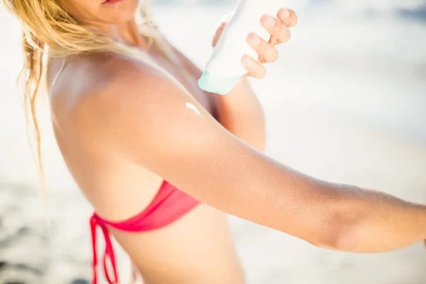 Mulher aplicando protetor solar loção na praia — Fotografia de Stock