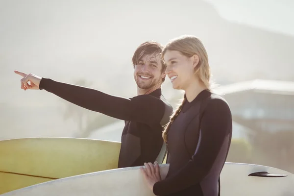 Casal com prancha de surf em pé na praia — Fotografia de Stock