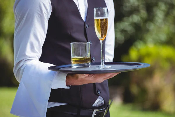 Garçom bonito segurando uma bandeja com bebidas — Fotografia de Stock