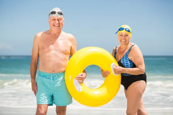 Casal sénior com anel de natação na praia — Fotografia de Stock