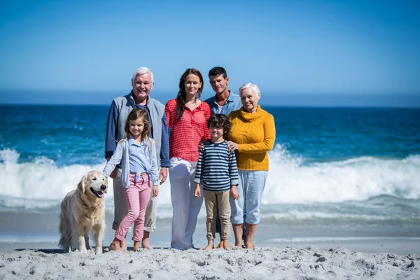 Família feliz com seu cão na praia — Fotografia de Stock