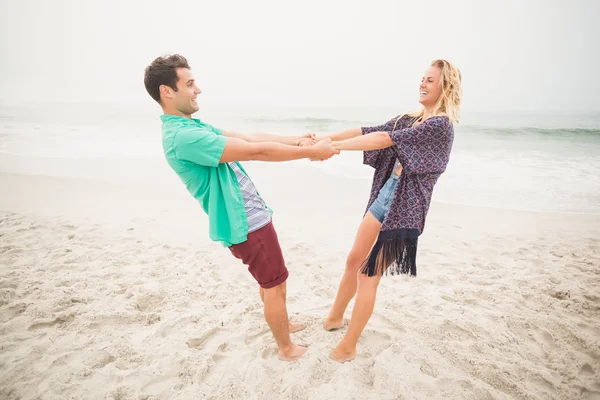 Gelukkige paar bedrijf handen op het strand — Stockfoto