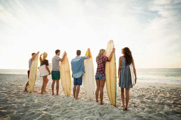 Amigos sosteniendo tabla de surf en la playa —  Fotos de Stock