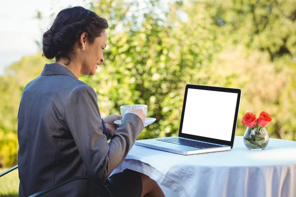 Bastante mujer de negocios tomando café y utilizando el ordenador portátil —  Fotos de Stock