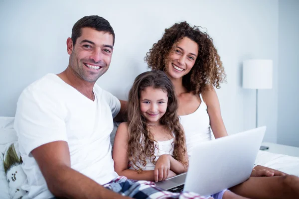 Portrait of couple using laptop with their daughter on bed — Stock Photo, Image