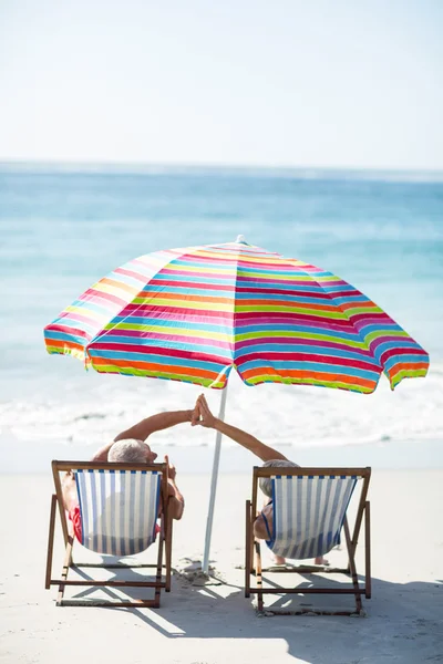 Cute mature couple doing high five on deckchairs — Stock Photo, Image