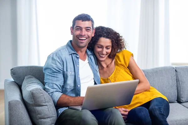 Jeune couple assis sur le canapé et utilisant un ordinateur portable — Photo