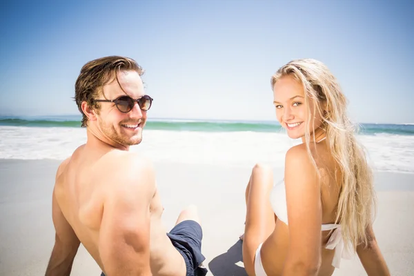 Счастливая пара сидит на пляже — стоковое фото