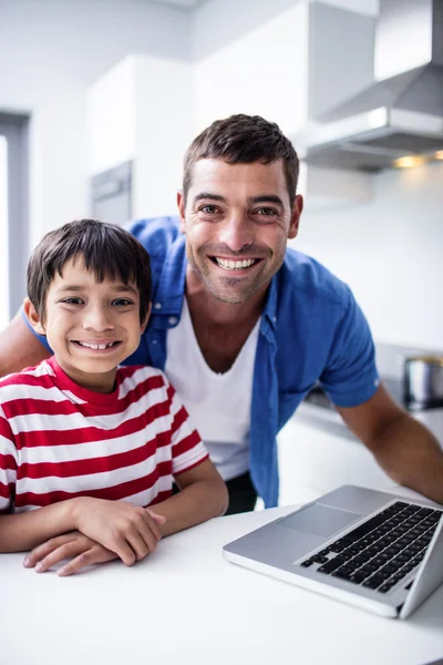 Portrait of father and son using laptop in kitchen — Stock Photo, Image