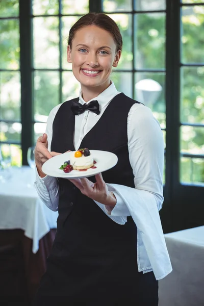 Camarera sonriente sosteniendo un plato — Foto de Stock