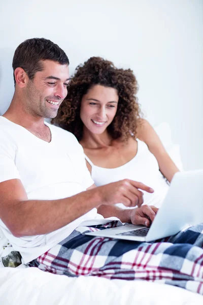 Счастливая пара с ноутбуком на кровати — стоковое фото