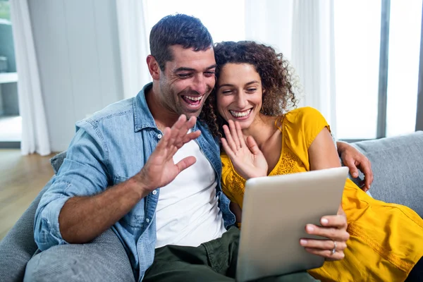 Casal feliz usando um tablet digital no sofá — Fotografia de Stock