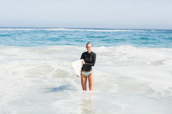 Donna in muta con in mano una tavola da surf sulla spiaggia — Foto Stock