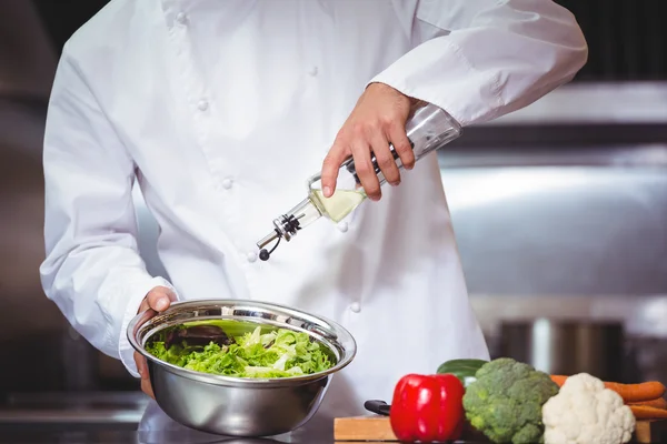 Koch gibt Öl auf Salat — Stockfoto