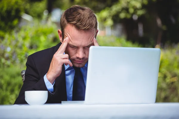 Uomo d'affari che utilizza il computer portatile con mal di testa — Foto Stock