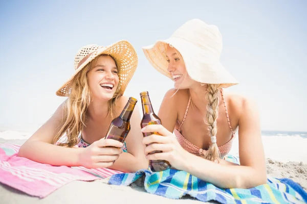Mujeres felices tumbadas en la playa con botella de cerveza —  Fotos de Stock