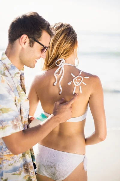 Человек делает символ солнца на спине женщины — стоковое фото