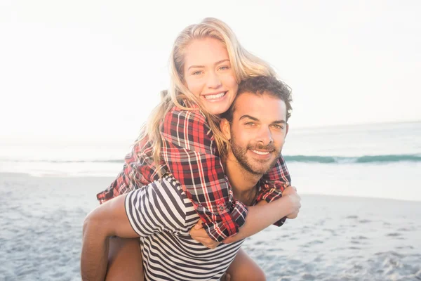 Joven hombre piggybacking hermosa mujer — Foto de Stock