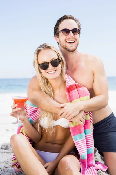 Молода пара в сонцезахисних окулярах обіймається на пляжі — стокове фото