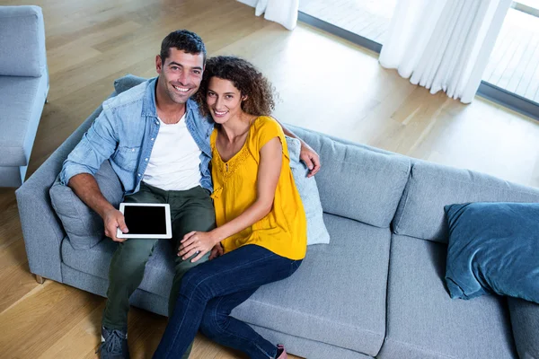 Pareja sentada en el sofá y utilizando la tableta digital — Foto de Stock