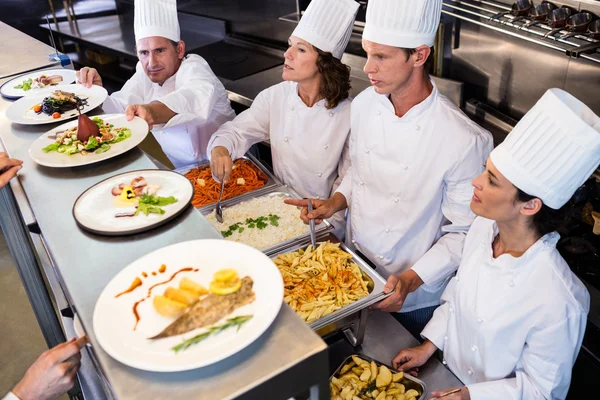 Chefs standing at serving trays — Stock Photo, Image