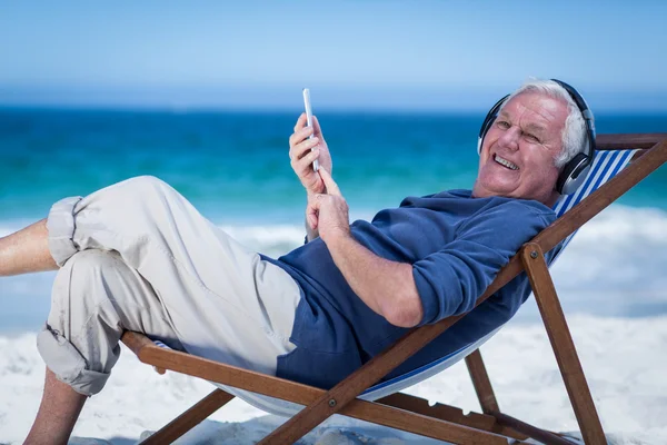 Man resting on a deck chair listening to music — Stock Photo, Image