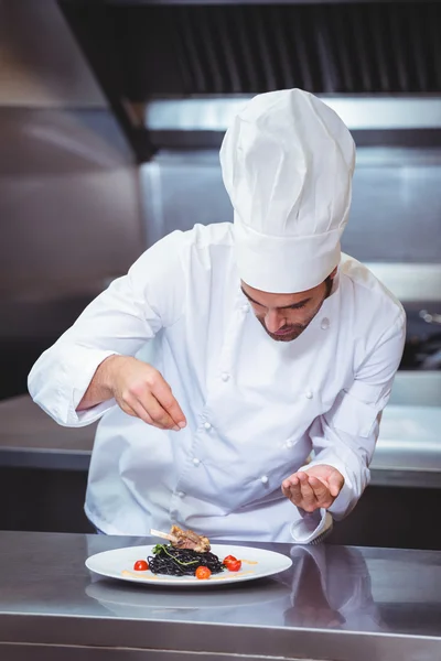 Koch streut Gewürze auf Teller — Stockfoto