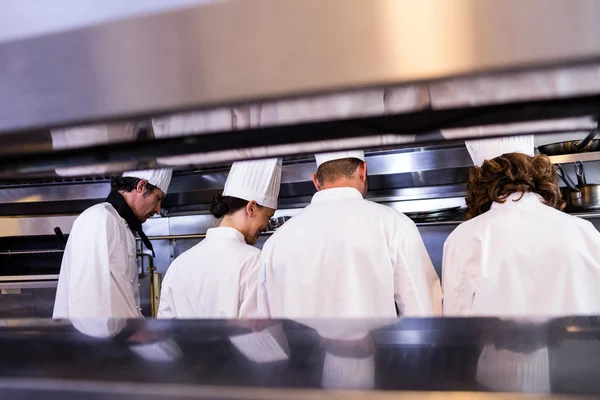 Groupe de chefs en uniforme blanc occupés à préparer la nourriture — Photo