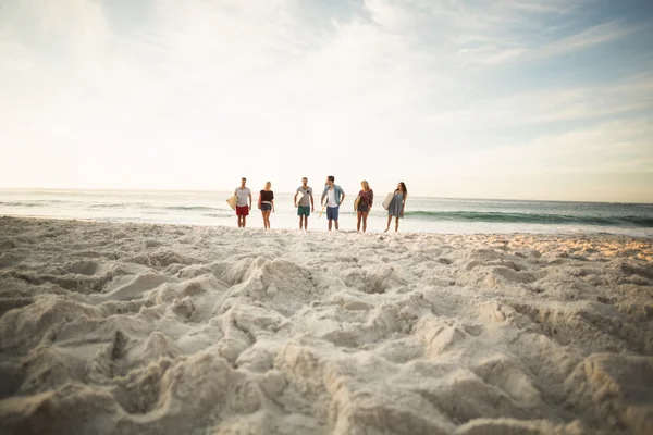 Друзья держат доску для серфинга на пляже — стоковое фото