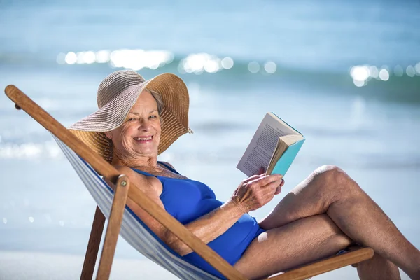 Жінка читає книгу, що лежить на стільці — стокове фото