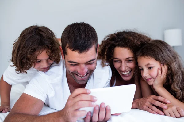 Щаслива сім'я використовує цифровий планшет на ліжку — стокове фото