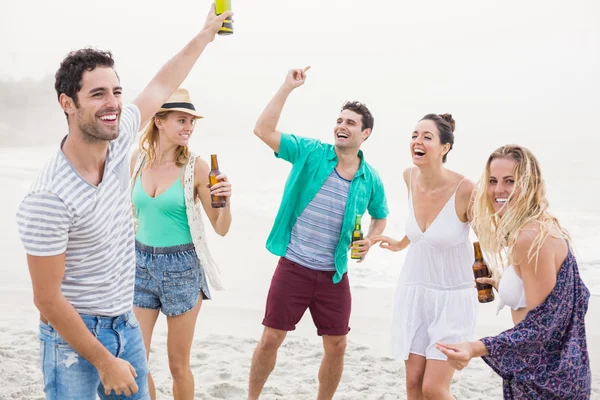 Grupo de amigos bailando en la playa con botellas de cerveza —  Fotos de Stock