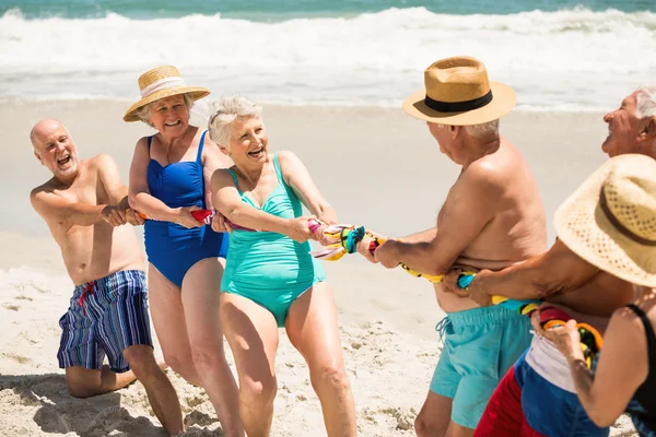 Старі люди грають на буксирі війни на пляжі — стокове фото