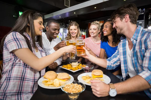 Amigos felizes tomando uma bebida e hambúrguer — Fotografia de Stock