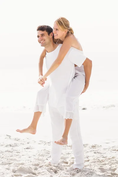 Muž dává prasátko zpět k ženě na pláži — Stock fotografie