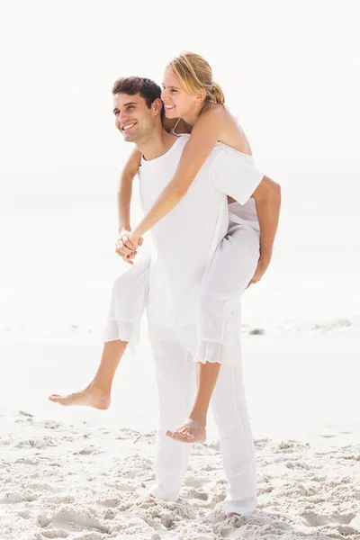 Homme donnant un cochon retour à la femme sur la plage — Photo