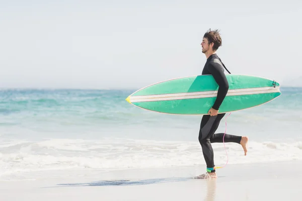 Uomo con tavola da surf che corre verso il mare — Foto Stock