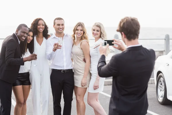 Goed geklede mensen fotograferen naast een limousine — Stockfoto