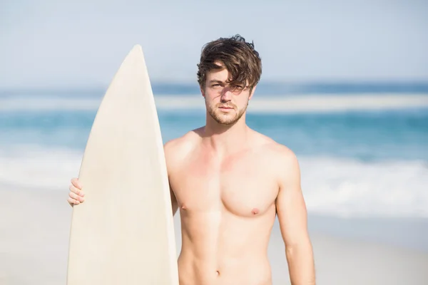 Bonito homem segurando prancha na praia — Fotografia de Stock