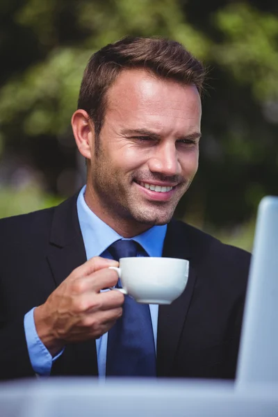 Empresário usando laptop tendo um café — Fotografia de Stock