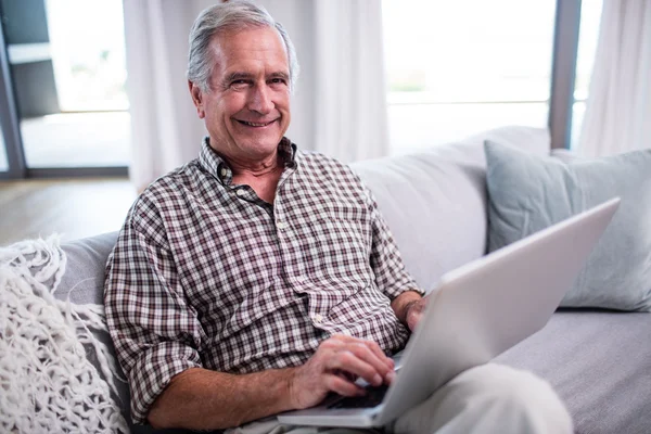 Portrét starší muže používat přenosný počítač v obývacím pokoji — Stock fotografie