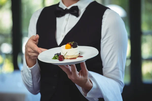 Garçonete segurando um prato com sobremesa — Fotografia de Stock