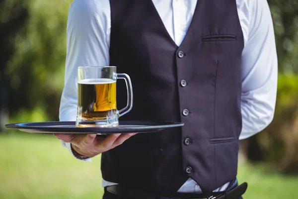 Przystojny kelner trzyma tacę z kufel piwa — Zdjęcie stockowe