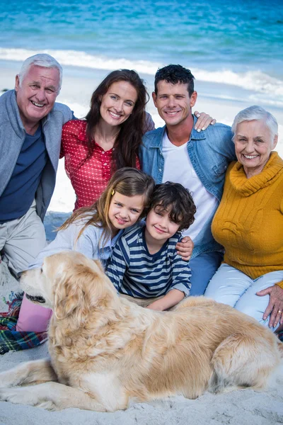 Família feliz com seu cão na praia — Fotografia de Stock