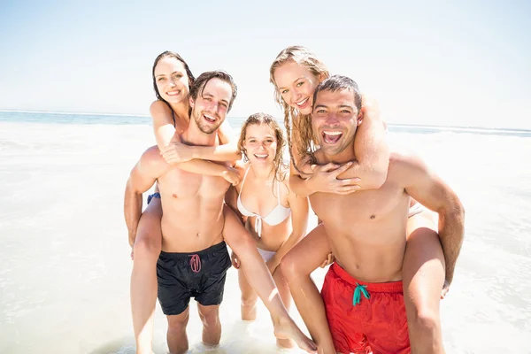 Mannen geven een piggy terug aan vrouwen op het strand — Stockfoto